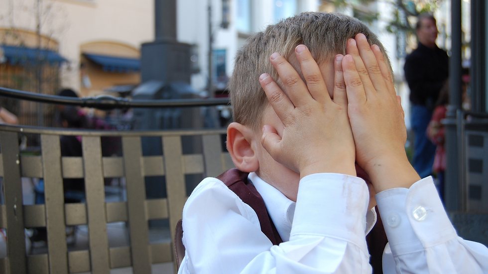 A little boy hiding his face in embarrassment.